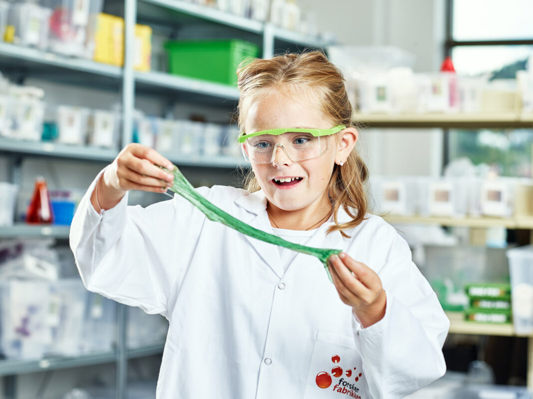 En jente i laboratoriefrakk leker med slim.